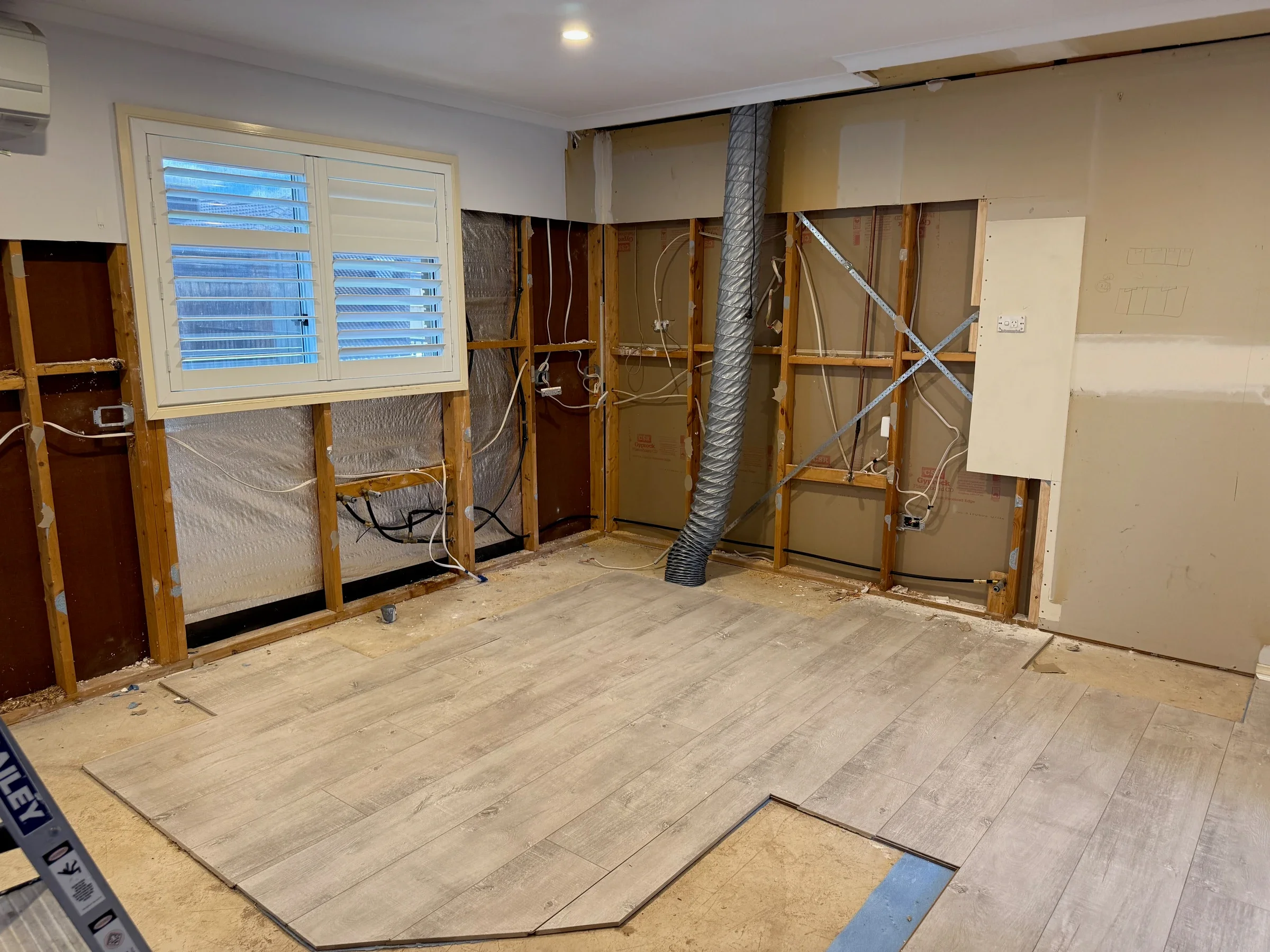 Bluestone kitchen during strip-out, with the old cabinetry removed and wall framing exposed