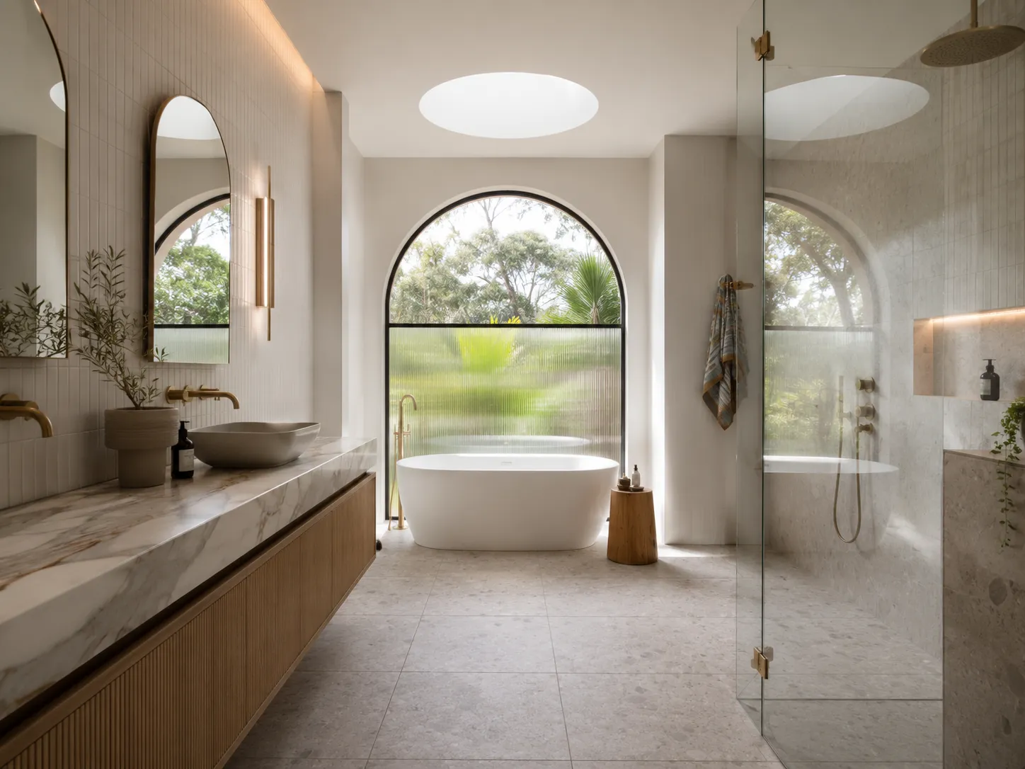 Completed bathroom with freestanding bath, stone vanity and arched window