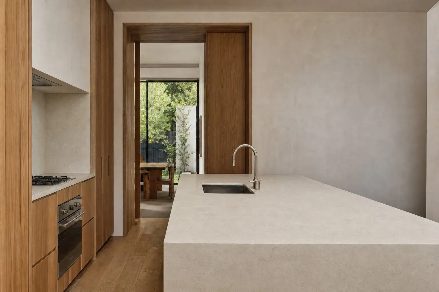 Warm timber kitchen with pale stone island and garden view